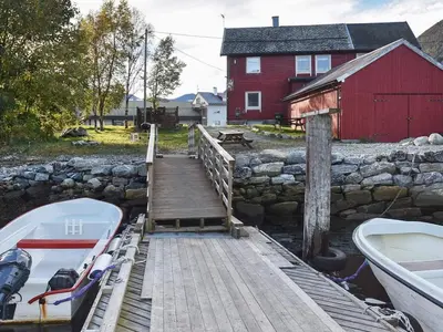 a dock with a boat next to a red barn at 2 person holiday home in Måndalen-By Traum in Sæbø