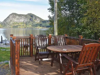 a wooden table and chairs on a deck near a lake at 2 person holiday home in Måndalen-By Traum in Sæbø