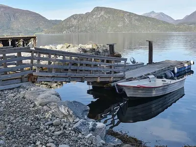 a boat is docked at a dock on a lake at 4 person holiday home in Måndalen-By Traum in Sæbø