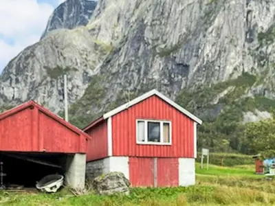 a red and white building in front of a mountain at 4 person holiday home in Eresfjord-By Traum in Øverås