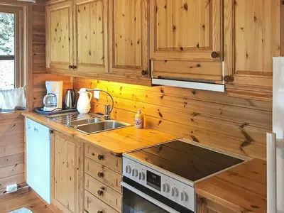 a kitchen with wooden cabinets and a stove top oven at 8 person holiday home in Norheimsund-By Traum in Norheimsund