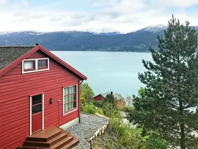 a red house with a view of a lake at 8 person holiday home in Norheimsund-By Traum in Norheimsund