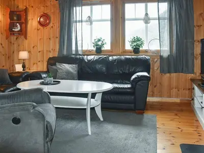 a living room with a black leather couch and a table at 7 person holiday home in Selje-By Traum in Selje