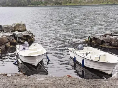 two boats are docked on the shore of a lake at 7 person holiday home in Selje-By Traum in Selje