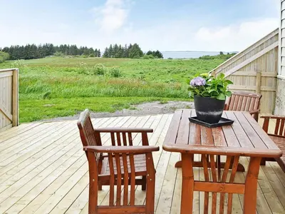 a wooden table with two chairs and a potted plant on a deck at 11 person holiday home in Fjørtoft-By Traum in Fjørtoft