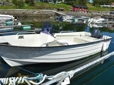 a white boat tied to a dock in the water at 9 person holiday home in Farstad-By Traum in Farstad