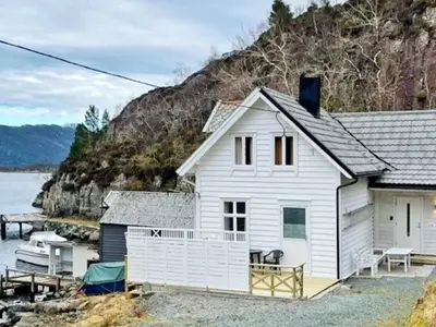 a white house next to a body of water at 6 person holiday home in Svelgen-By Traum in Sørgulen