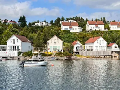 a small boat in the water in front of houses at 9 person holiday home in GURSKØY-By Traum in Kjellsund