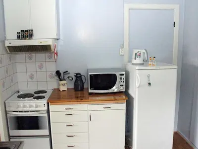 a small kitchen with a white refrigerator and a microwave at 4 person holiday home in VÅGLAND-By Traum in Rabben
