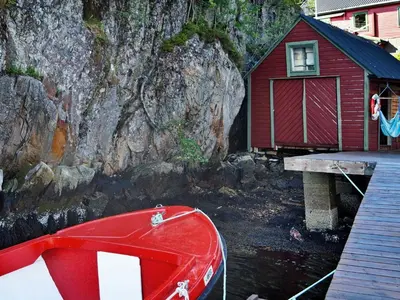a red house and a boat next to a building at 10 person holiday home in HOSTELAND-By Traum in Hosteland