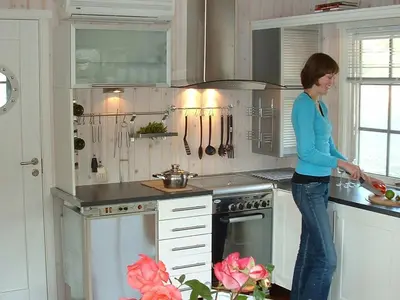 a woman standing in a kitchen preparing food at 6 person holiday home in Kalvåg-By Traum in Kalvåg