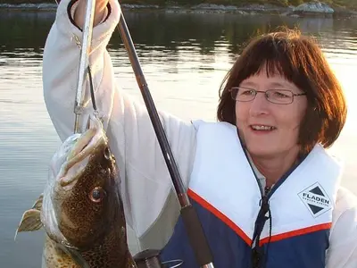 a woman holding a fish on a pole in the water at 6 person holiday home in Kalvåg-By Traum in Kalvåg