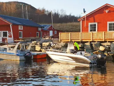 two boats are docked in a marina next to a red house at 6 person holiday home in Oksvoll-By Traum in Oksvoll