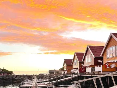 a group of houses on a dock with a sunset at 6 person holiday home in Gursken-By Traum in Larsnes