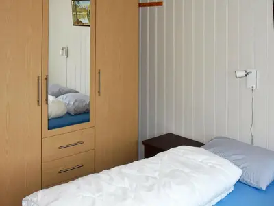 a bedroom with a bed and a cabinet with a mirror at 7 person holiday home in Blaksæter-By Traum in Sølberg