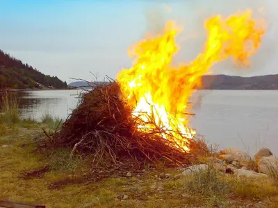 a bonfire in the grass next to a body of water at 10 person holiday home in Follafoss-By Traum in Vølset