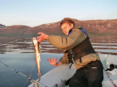 a man is holding a fish on a boat at 10 person holiday home in Follafoss-By Traum in Vølset