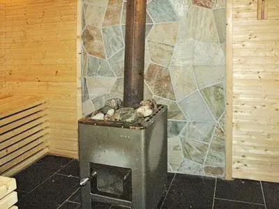 a wood stove in a room with a stone wall at 8 person holiday home in VEVANG-By Traum in Vevang