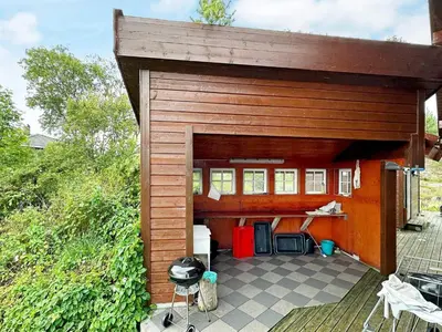 a wooden garage with a table and a grill at 8 person holiday home in VEVANG-By Traum in Vevang