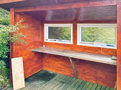 a wooden cabin with a bench and two windows at 5 person holiday home in VEVANG-By Traum in Vevang