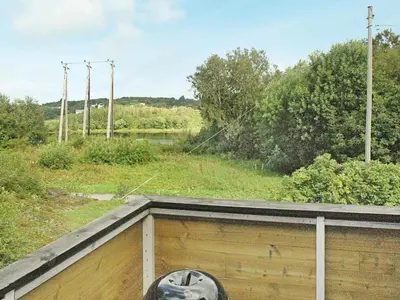 a person sitting on top of a wooden fence at 5 person holiday home in VEVANG-By Traum in Vevang