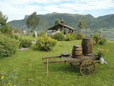 a wooden cart with barrels on it in a field at 11 person holiday home in Syvde in Myklebost
