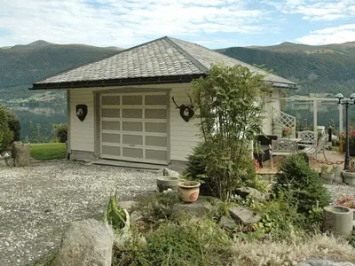 a small house with a garage with mountains in the background at 11 person holiday home in Syvde in Myklebost
