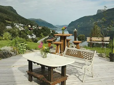 a bench and table on a patio with a view of the water at 11 person holiday home in Syvde in Myklebost
