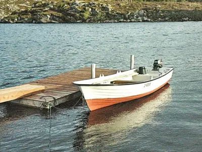 a boat sitting on the water next to a dock at 12 person holiday home in Kvenvær in Kvenvær