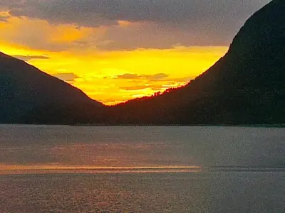 a sunset over a body of water with mountains at 6 person holiday home in Halsanaustan in Korsnes