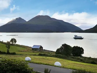 a boat in a lake with a house and a boat at 6 person holiday home in Halsanaustan in Korsnes