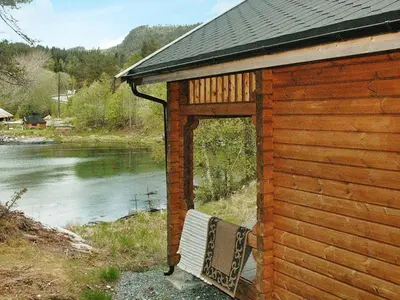 a building with a bench next to a river at 5 person holiday home in VÅGLAND in Bårdset
