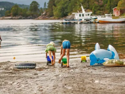 two people are playing on the shore of a beach at 5 person holiday home in VÅGLAND in Bårdset