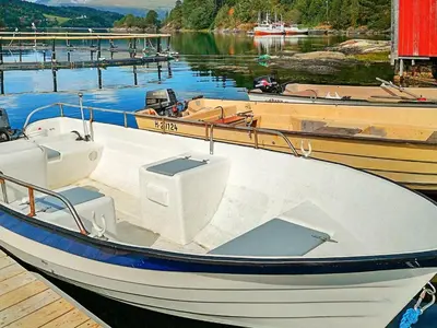 a white boat is docked at a dock at 5 person holiday home in VÅGLAND in Bårdset