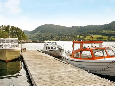 three boats are docked at a dock in the water at 5 person holiday home in VÅGLAND in Bårdset