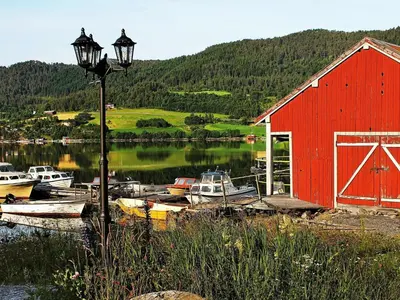 a red barn and boats in a body of water at 5 person holiday home in VÅGLAND in Bårdset