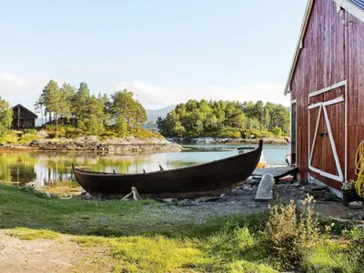 a boat sitting on the grass next to a barn at 5 person holiday home in VÅGLAND in Bårdset