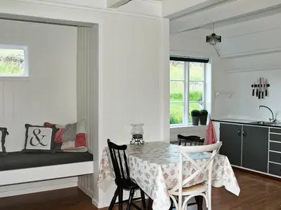a kitchen and dining room with a table and chairs at 5 person holiday home in VÅGLAND in Bårdset