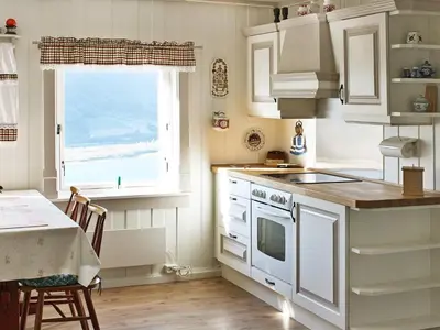 a kitchen with white cabinets and a table and a window at 6 person holiday home in Otta in Otta