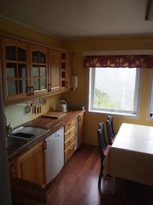 a kitchen with wooden cabinets and a table and a window at Lunheim in Geiranger in Geiranger