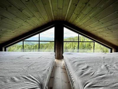 two beds in a room with a large window at Fjellgla tretopphytte in Holo