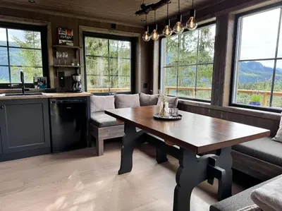 a kitchen and living room with a wooden table at Fjellgla tretopphytte in Holo