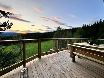 a wooden deck with a bench and a view at Fjellgla tretopphytte in Holo