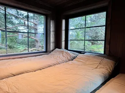 a bed in a room with three windows at Fjellgla tretopphytte in Holo