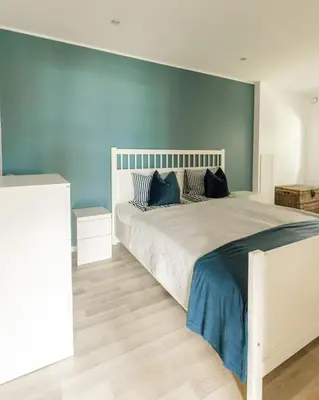 a bedroom with a large bed with a blue wall at Vestre apartment in Ålesund