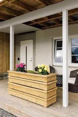 a wooden planter with flowers on a patio at Vestre apartment in Ålesund