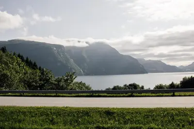 a road next to a body of water with mountains at Vestre apartment in Ålesund