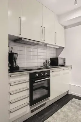 a kitchen with white cabinets and a black oven at 500 m til Bryggen I Skjermet Uteplass! in Bergen