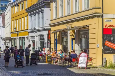 a group of people sitting in chairs on a city street at 500 m til Bryggen I Skjermet Uteplass! in Bergen
