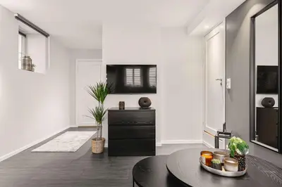 a living room with a table and a black cabinet at 500 m til Bryggen I Skjermet Uteplass! in Bergen